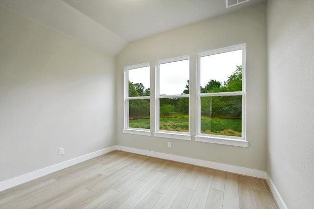 spare room featuring baseboards, visible vents, lofted ceiling, and light wood-type flooring