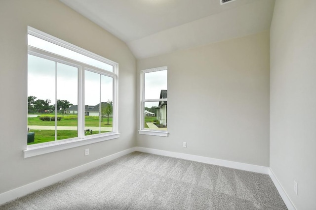empty room with carpet floors, baseboards, and lofted ceiling