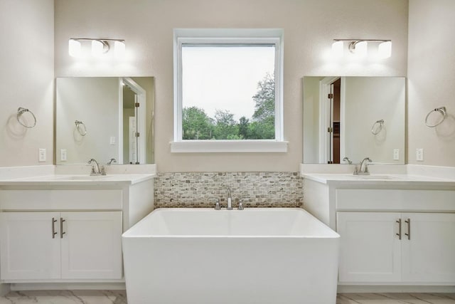 bathroom featuring a soaking tub, two vanities, and a sink