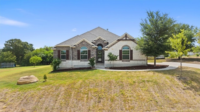 view of front facade featuring a front yard, brick siding, and roof with shingles