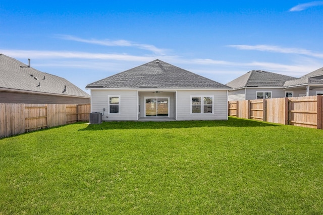 rear view of house with roof with shingles, a fenced backyard, cooling unit, and a lawn