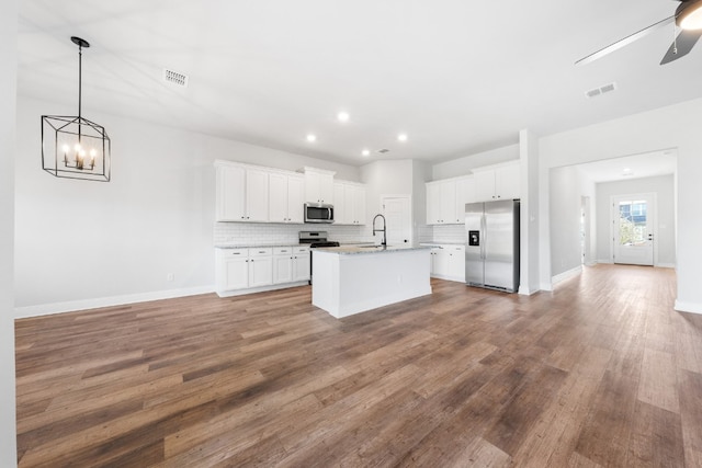 kitchen featuring visible vents, a center island with sink, white cabinetry, and stainless steel appliances