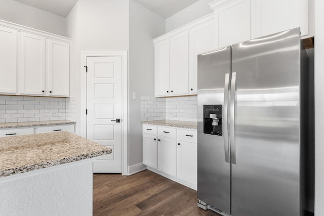 kitchen with dark wood finished floors, tasteful backsplash, white cabinets, light stone countertops, and stainless steel fridge with ice dispenser