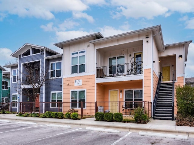 view of property with uncovered parking and stairway