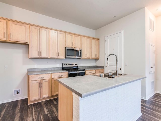 kitchen featuring stainless steel appliances, light countertops, a sink, and a center island with sink