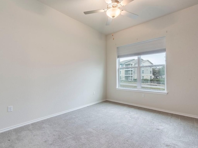 carpeted spare room with ceiling fan and baseboards