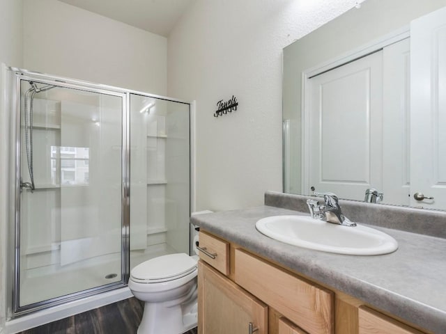 full bathroom featuring toilet, a shower stall, wood finished floors, and vanity