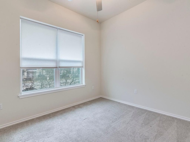 carpeted spare room with a ceiling fan and baseboards