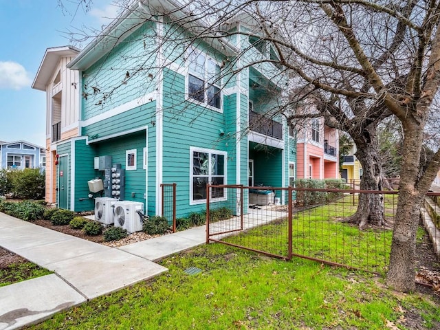 view of side of home featuring ac unit, fence private yard, and a lawn