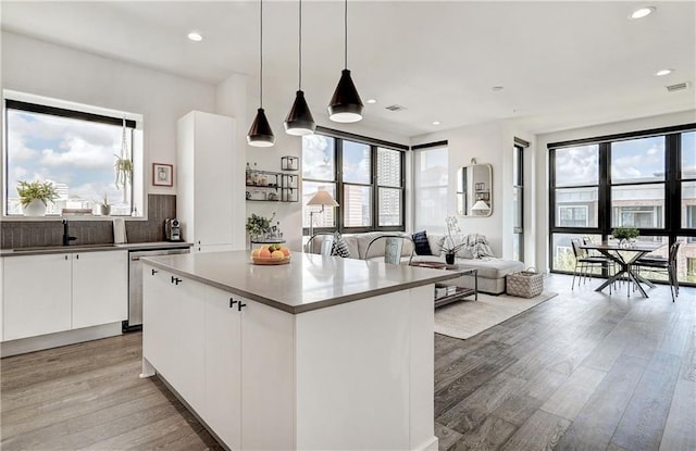 kitchen with decorative light fixtures, open floor plan, white cabinets, a kitchen island, and modern cabinets