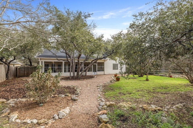 rear view of property with a yard, a fenced backyard, and a sunroom