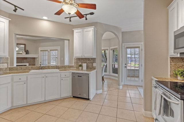 kitchen featuring tile countertops, ceiling fan, stainless steel appliances, white cabinetry, and a sink