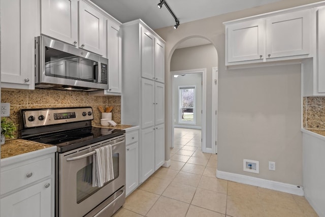 kitchen featuring light tile patterned floors, white cabinetry, appliances with stainless steel finishes, and arched walkways