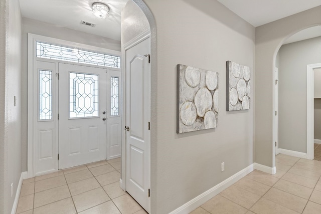 entrance foyer with arched walkways, visible vents, baseboards, and light tile patterned flooring