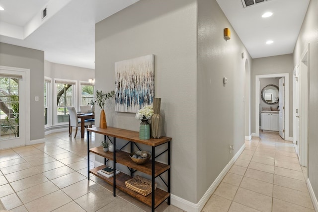 hallway with visible vents, baseboards, and light tile patterned floors