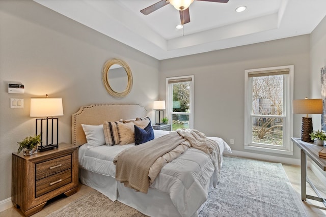 bedroom featuring a tray ceiling, multiple windows, and recessed lighting