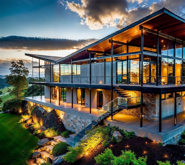 back of property featuring stone siding, stairway, and a patio