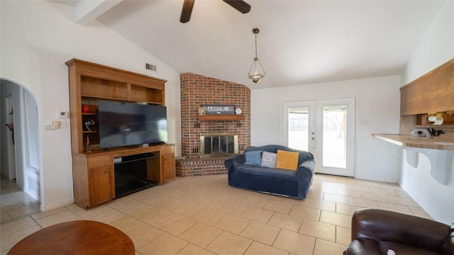 living room featuring lofted ceiling with beams, a fireplace, arched walkways, and visible vents