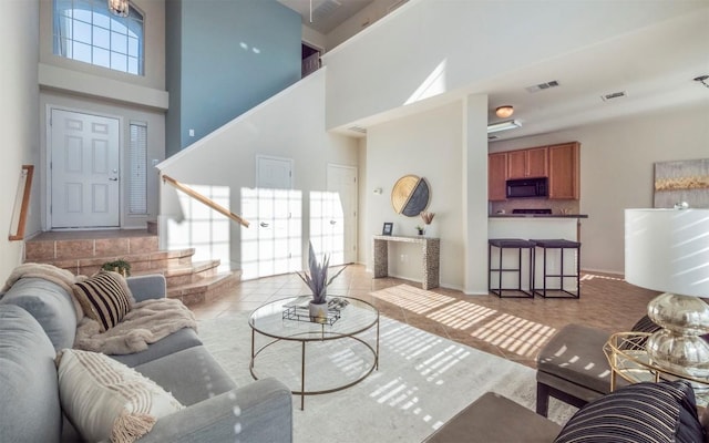 living room featuring stairs, a high ceiling, light tile patterned flooring, and visible vents