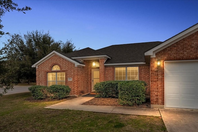 ranch-style home with a garage, brick siding, a shingled roof, and a front lawn