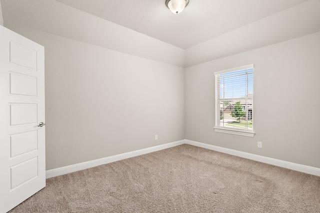 empty room featuring carpet, baseboards, and vaulted ceiling