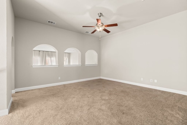 carpeted empty room with baseboards, visible vents, and a ceiling fan