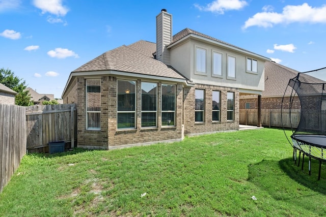 rear view of house featuring a fenced backyard, a trampoline, a chimney, and a yard