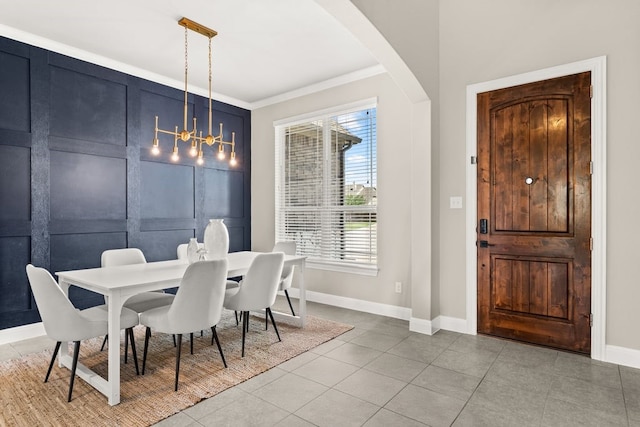 tiled dining space featuring arched walkways, baseboards, a chandelier, and crown molding