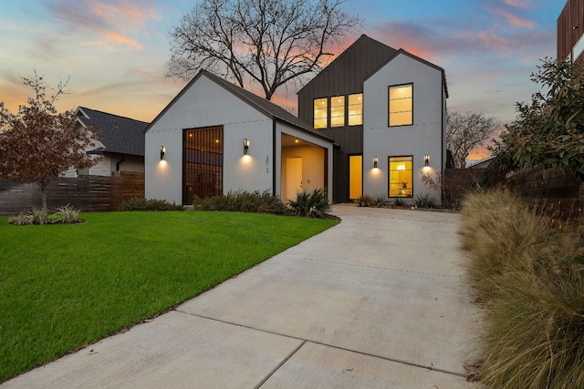 view of front facade with a garage, concrete driveway, fence, a front yard, and stucco siding