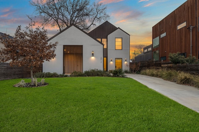 modern home featuring a yard, fence, driveway, and stucco siding