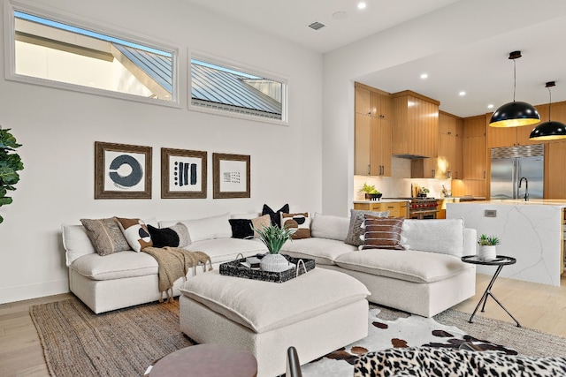 living area with light wood-type flooring, visible vents, baseboards, and recessed lighting