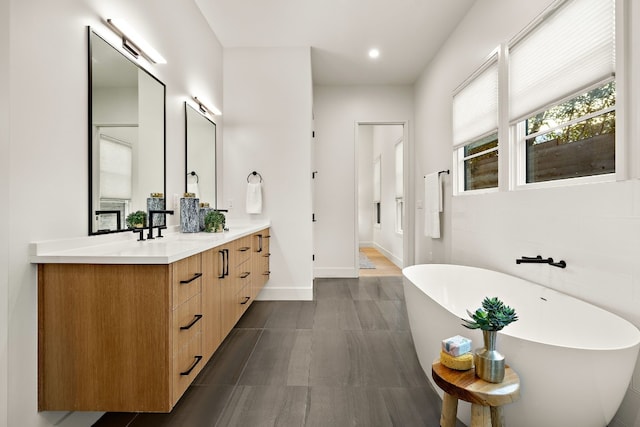 bathroom with a freestanding tub, recessed lighting, baseboards, and vanity