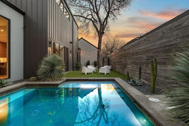 pool at dusk featuring a fenced backyard and a fenced in pool