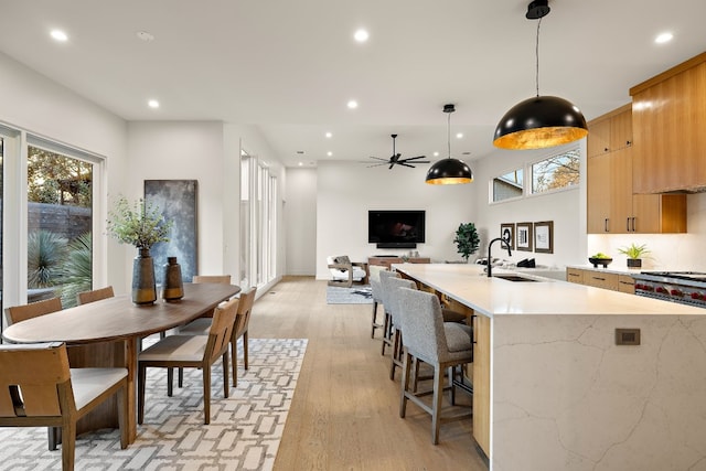 kitchen featuring a sink, hanging light fixtures, light brown cabinetry, light wood finished floors, and modern cabinets