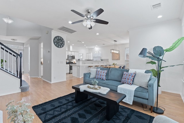 living area with light wood-type flooring, visible vents, and stairway