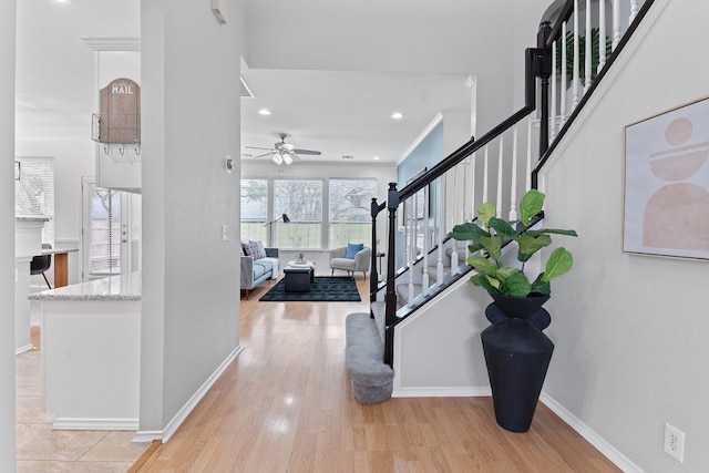 foyer entrance with light wood finished floors, baseboards, ceiling fan, stairway, and recessed lighting