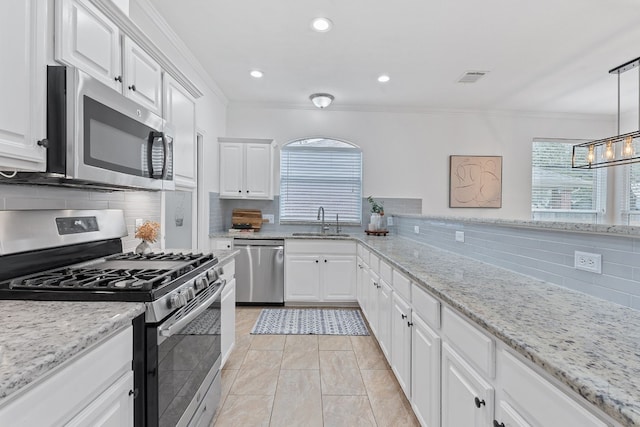 kitchen with white cabinets, stainless steel appliances, a sink, and hanging light fixtures