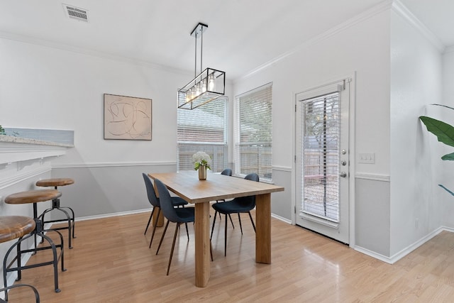 dining area featuring baseboards, light wood-style flooring, visible vents, and crown molding