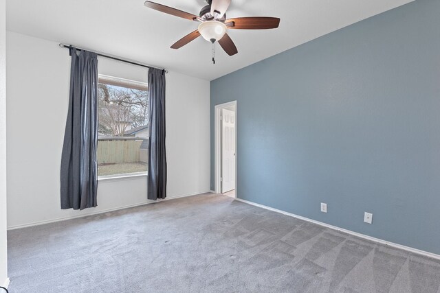 carpeted empty room featuring ceiling fan and baseboards