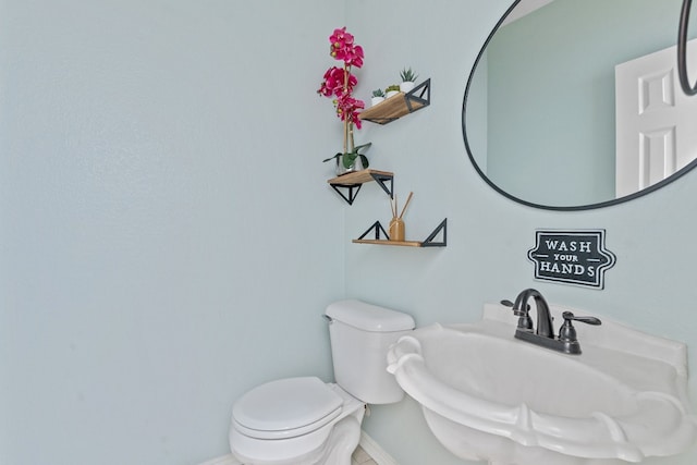 bathroom featuring baseboards, a sink, and toilet