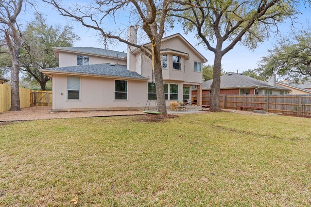 back of property with a patio, a lawn, a chimney, and a fenced backyard