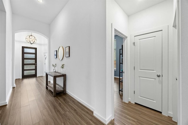 foyer entrance with baseboards, a wealth of natural light, a chandelier, and dark wood finished floors