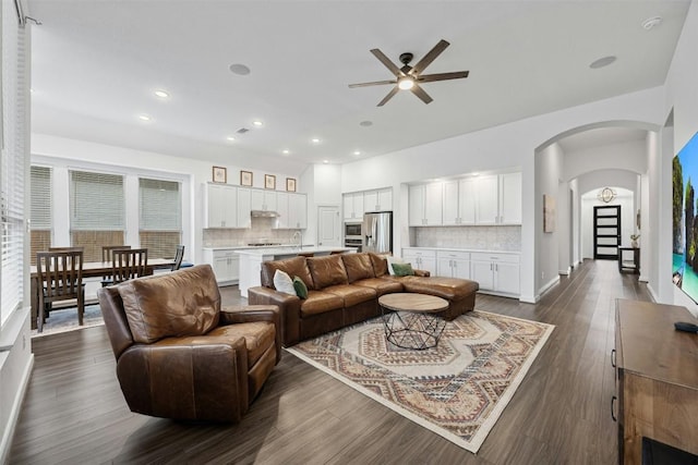 living room with arched walkways, a ceiling fan, dark wood-type flooring, and recessed lighting