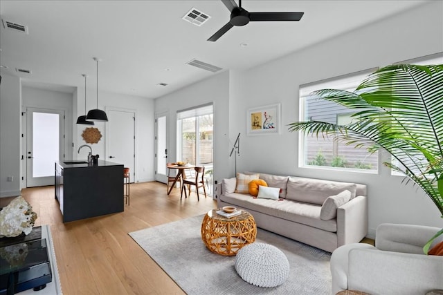 living area with light wood-style floors, visible vents, and a ceiling fan