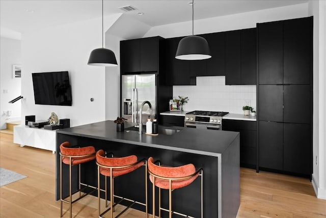 3204 Garden Villa Ln Unit 2, Austin, TX 78704 - kitchen with dark cabinets, appliances with stainless steel finishes, a sink, and pendant lighting
