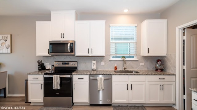 6205 Conestoga Wagon Way, Del Valle, TX 78617 - kitchen featuring stainless steel appliances, a sink, white cabinetry, tasteful backsplash, and recessed lighting