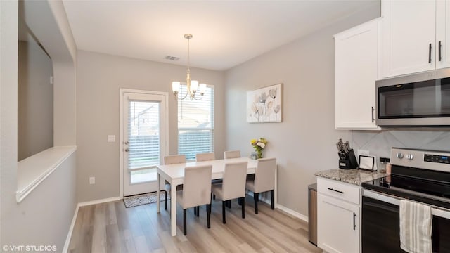 6205 Conestoga Wagon Way, Del Valle, TX 78617 - dining room featuring a chandelier, light wood-type flooring, and baseboards