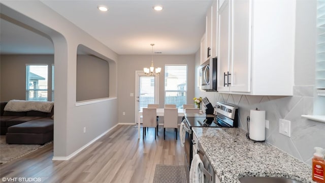 6205 Conestoga Wagon Way, Del Valle, TX 78617 - kitchen with appliances with stainless steel finishes, a chandelier, light wood finished floors, white cabinetry, and tasteful backsplash