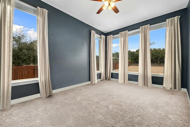 carpeted empty room with ceiling fan and baseboards