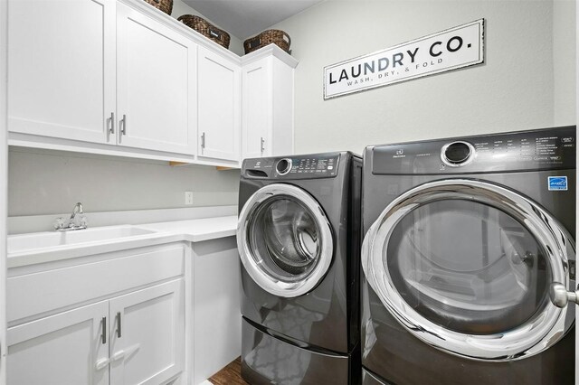 clothes washing area with cabinet space, separate washer and dryer, and a sink